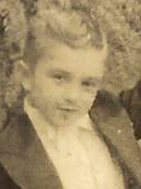 Clique aqui para conhecer (ou lembrar) e curtir, um pouco da história pessoal de Joaquim Assis, desde a infância. 
Descrevemos para você: sobre fundo sépia, vemos a foto pb esmaecida de Joaquim Assis menino, até a altura do peito, braço esquerdo levantado, vestido de smoking com um bigodinho pintado, sorrindo para nós.