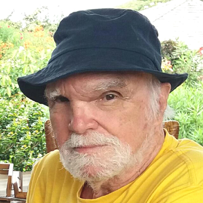 Descrevemos para você esta página de boas-vindas: à esquerda da página, uma imagem de Joaquim Assis voltado para a esquerda da tela, a 3/4 de perfil, seu olhar se volta para nós, com um leve sorriso. Ele usa blusa amarela e chapéu de brim azul marinho, é branco, olhos castanhos, tem barba e cabelo brancos. Ao fundo uma vegetação. À esquerda da foto, trecho de música composta por ele escrita em pauta. 